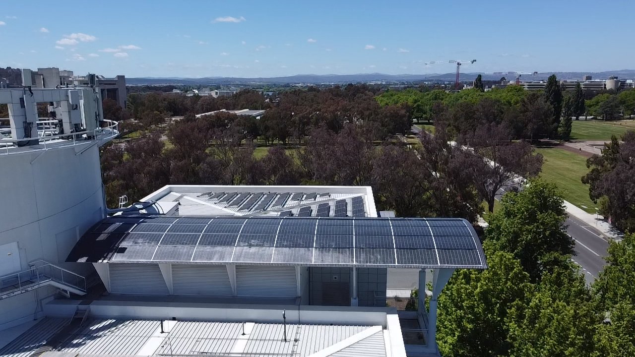 Drone view of the curved solar canopy on the Questacon roof with Canberra hills behind